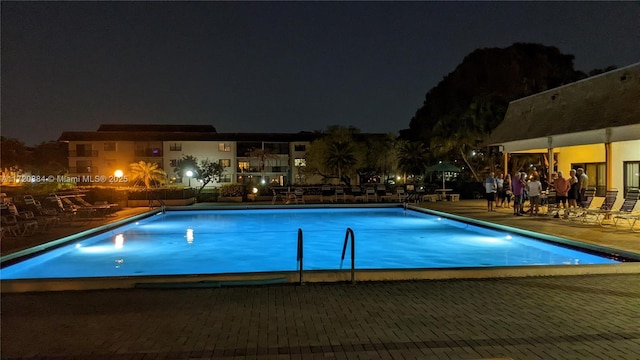 pool at twilight featuring a patio