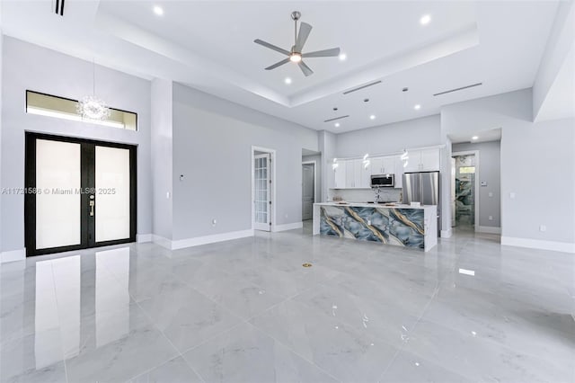 unfurnished living room with a tray ceiling and french doors