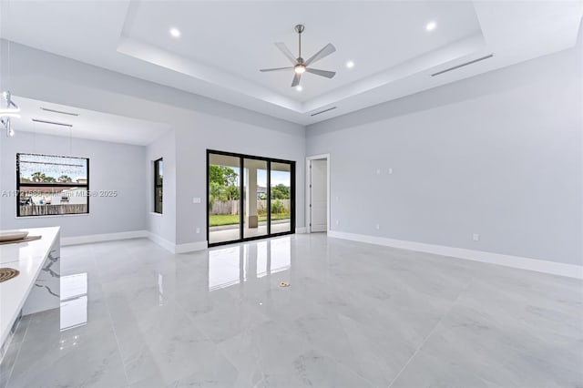 empty room featuring ceiling fan and a raised ceiling