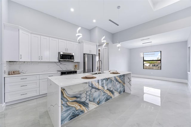 kitchen featuring white cabinets, decorative backsplash, a kitchen island with sink, and appliances with stainless steel finishes