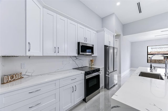 kitchen with light stone counters, sink, white cabinets, and stainless steel appliances