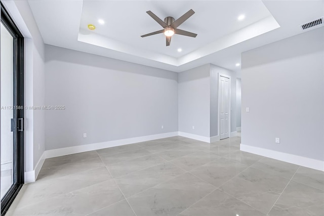 empty room with a tray ceiling and ceiling fan