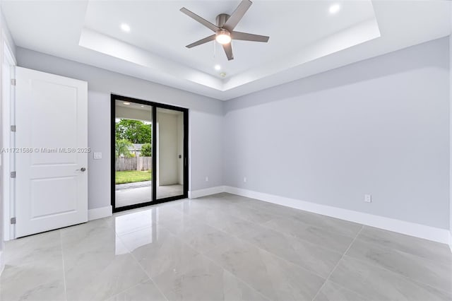 spare room with a tray ceiling and ceiling fan