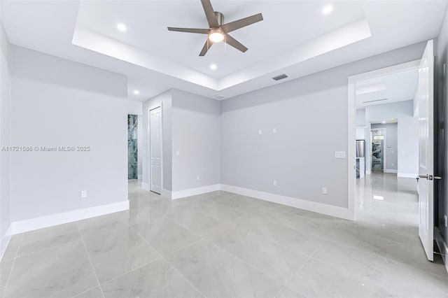 empty room featuring a raised ceiling and ceiling fan