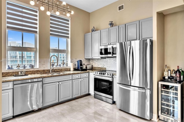 kitchen featuring wine cooler, appliances with stainless steel finishes, a sink, and gray cabinetry