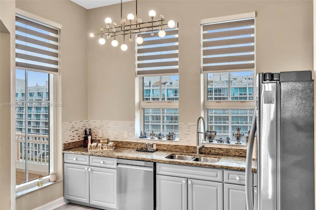 kitchen with white cabinetry, sink, stainless steel appliances, decorative light fixtures, and decorative backsplash