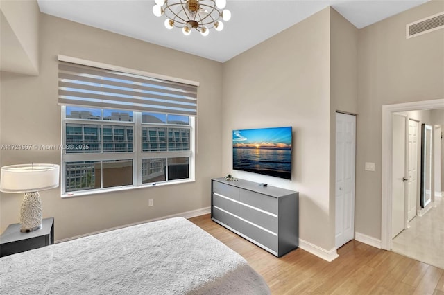 bedroom with a notable chandelier, a closet, multiple windows, and light hardwood / wood-style flooring