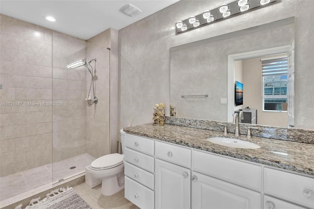 full bath featuring tiled shower, vanity, toilet, and tile patterned floors