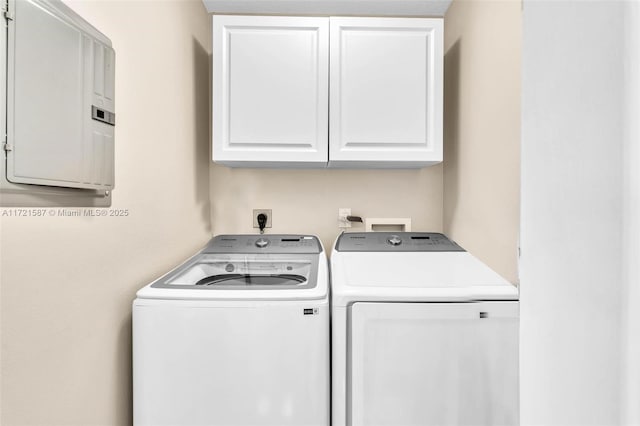 laundry area featuring electric panel, cabinets, and washer and dryer