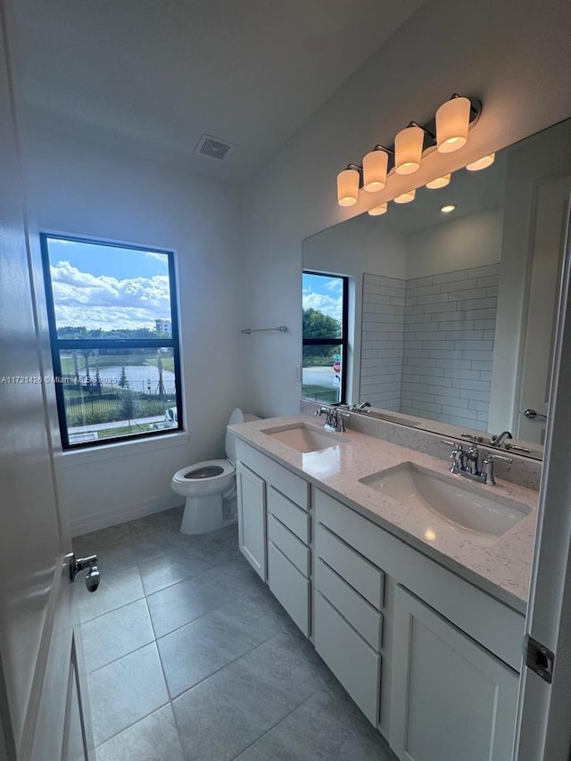 bathroom with tile patterned floors, a wealth of natural light, vanity, and toilet