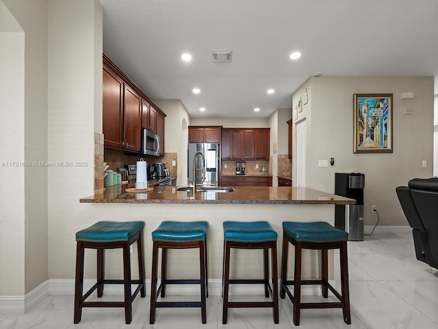 kitchen featuring backsplash, kitchen peninsula, sink, and appliances with stainless steel finishes