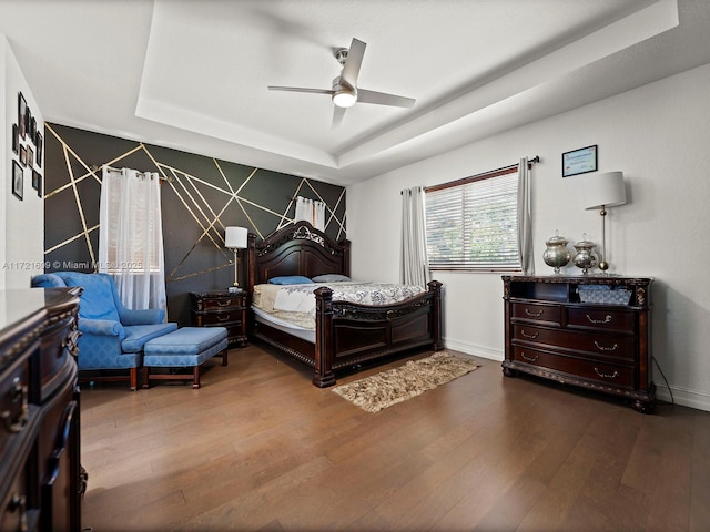 bedroom with a tray ceiling, ceiling fan, and hardwood / wood-style flooring