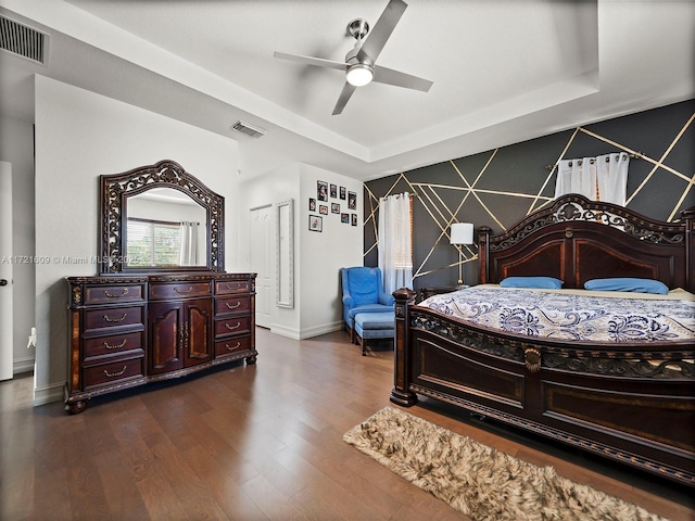 bedroom with dark hardwood / wood-style floors, a raised ceiling, and ceiling fan