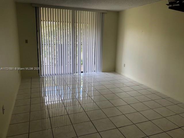 tiled empty room featuring a textured ceiling