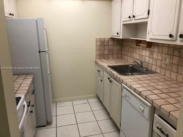 kitchen featuring tasteful backsplash, white appliances, sink, tile countertops, and light tile patterned flooring