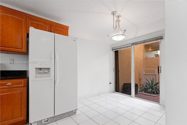 kitchen featuring white refrigerator with ice dispenser, hanging light fixtures, and light tile patterned flooring