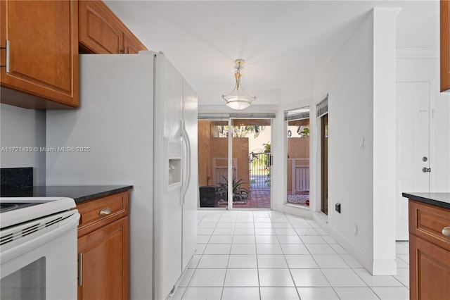 kitchen featuring dark stone counters, pendant lighting, light tile patterned floors, and white electric range oven