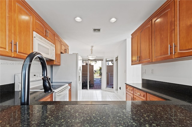 kitchen featuring light tile patterned flooring, hanging light fixtures, and dark stone counters