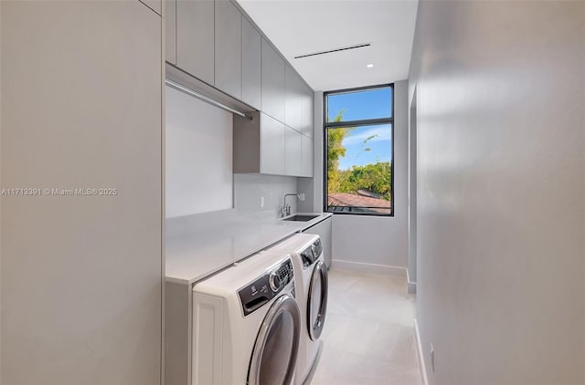 laundry room with washer and clothes dryer, a sink, cabinet space, and baseboards