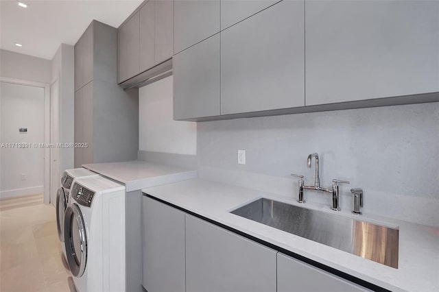 laundry area with cabinet space, washer and dryer, and a sink