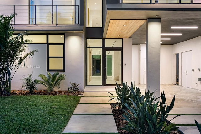 doorway to property featuring french doors, a balcony, and stucco siding