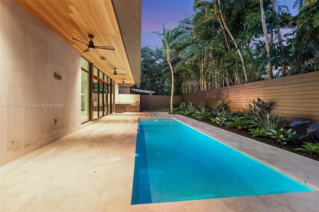 pool at dusk with a patio area, a fenced backyard, ceiling fan, and a fenced in pool