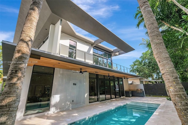 rear view of property featuring ceiling fan, a patio, a balcony, and stucco siding