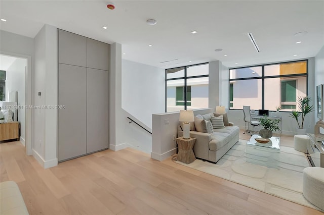 living room featuring light wood-type flooring, baseboards, and recessed lighting