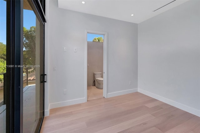 unfurnished bedroom featuring recessed lighting, multiple windows, baseboards, and wood finished floors