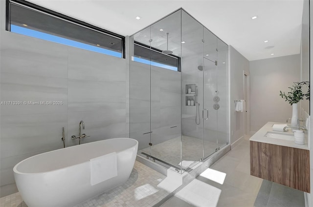 full bath with a shower stall, tile walls, a freestanding bath, and tile patterned floors