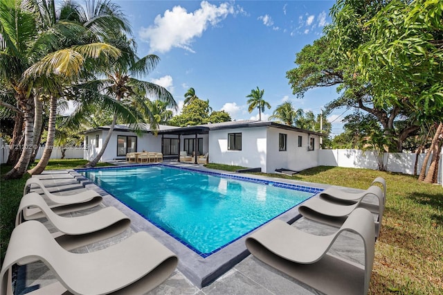 view of swimming pool with a sunroom and a lawn