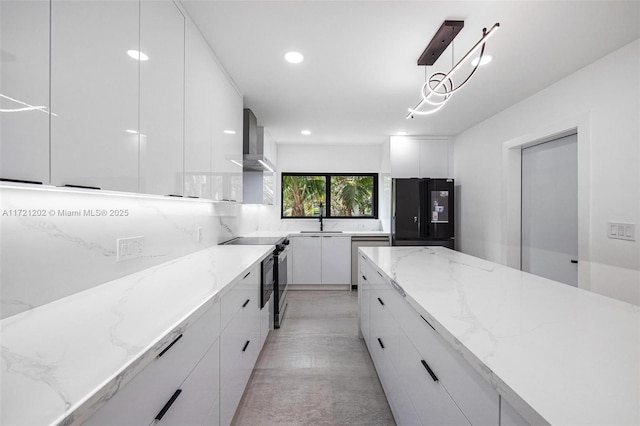 kitchen with pendant lighting, white cabinetry, light stone counters, stainless steel appliances, and wall chimney exhaust hood