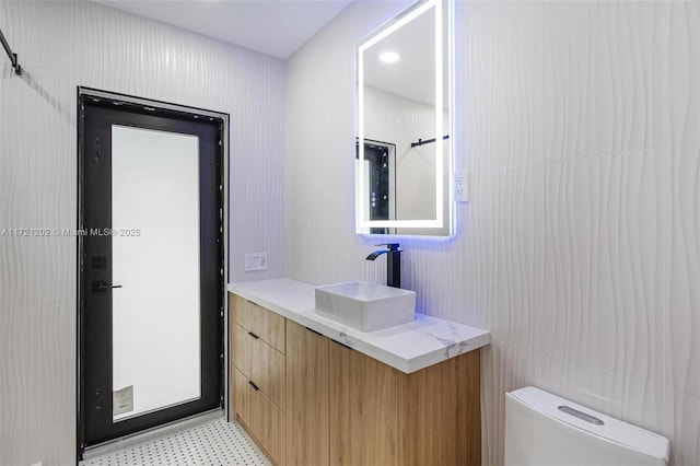 bathroom with vanity, toilet, and tile walls