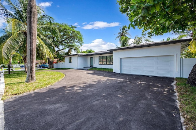 ranch-style house featuring a garage and a front lawn