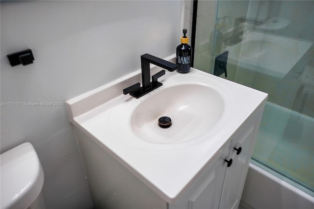 full bathroom with combined bath / shower with glass door, vanity, and toilet