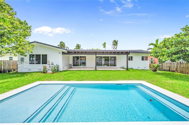 rear view of property with a lawn, a patio area, and a fenced in pool