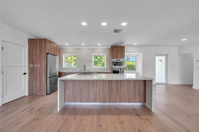 kitchen featuring a large island, stainless steel appliances, and light hardwood / wood-style flooring