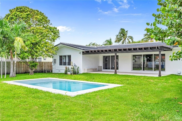 rear view of property with a fenced in pool, a patio area, and a lawn