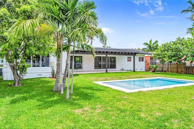 back of property with a yard and a fenced in pool