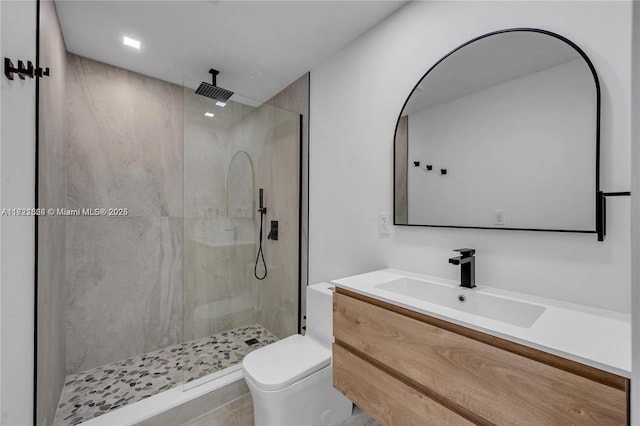 bathroom with tile patterned floors, vanity, toilet, and tiled shower