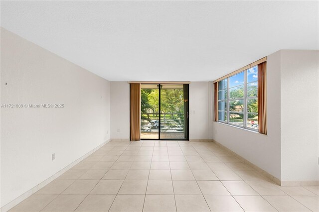 unfurnished room featuring light tile patterned floors and a wall of windows