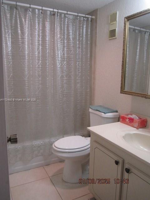 full bathroom featuring tile patterned floors, toilet, a textured ceiling, vanity, and shower / bath combo