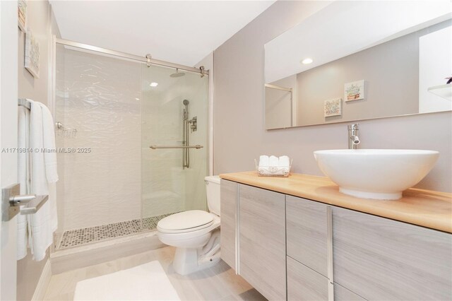 bathroom featuring vanity, an enclosed shower, and toilet