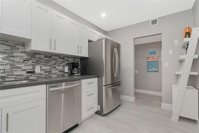 kitchen featuring white cabinets, light hardwood / wood-style floors, stainless steel appliances, and tasteful backsplash