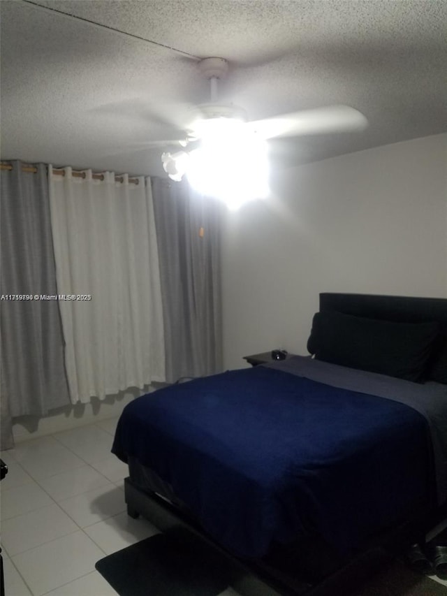 tiled bedroom with ceiling fan and a textured ceiling