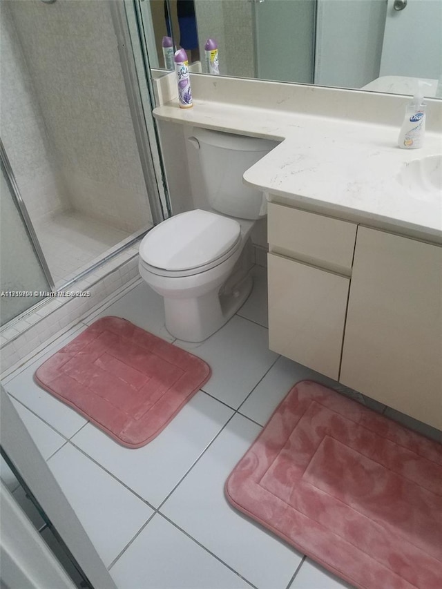 bathroom with tile patterned flooring, vanity, toilet, and a shower with door