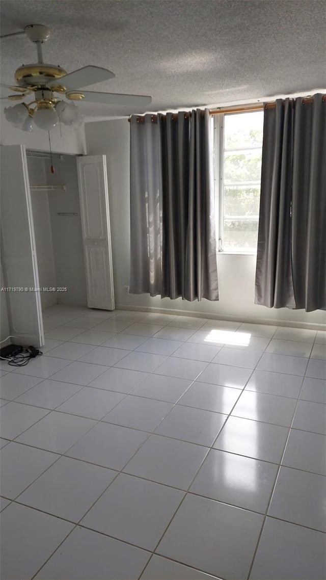 tiled spare room with ceiling fan and a textured ceiling