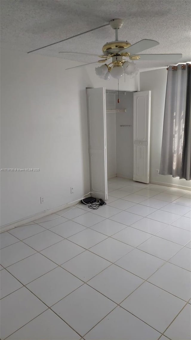 unfurnished bedroom with light tile patterned floors, a textured ceiling, a closet, and ceiling fan