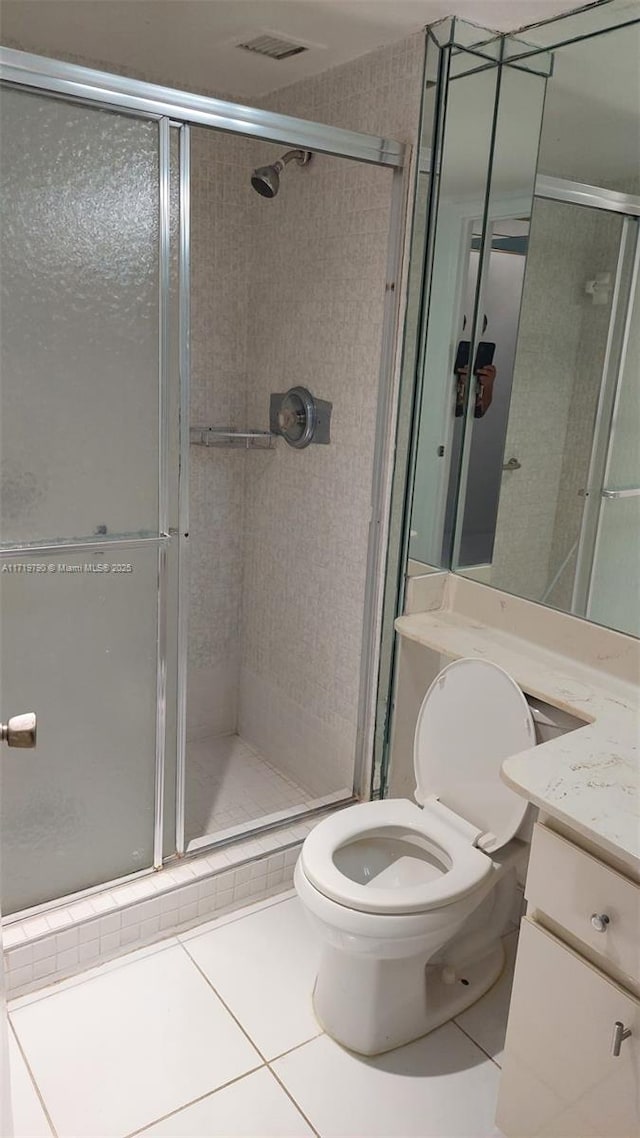 bathroom featuring tile patterned flooring, vanity, toilet, and an enclosed shower