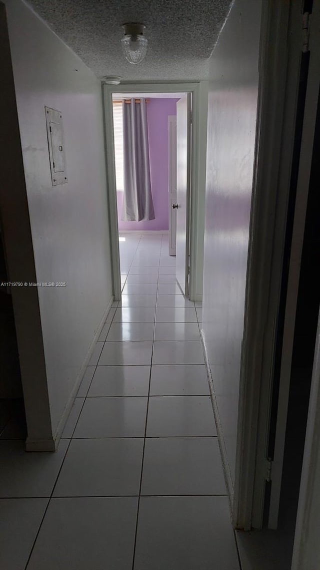 corridor with light tile patterned floors and a textured ceiling